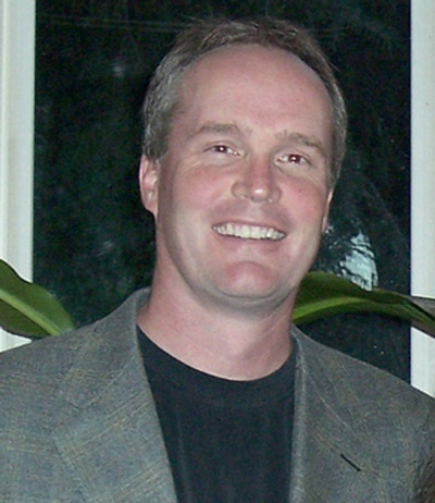 Man smiling in front of plant, a patient at Karl Hoffman Dentistry in Lacey, WA