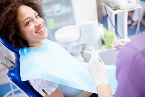 Smiling woman in dental chair looking up at dental assistant